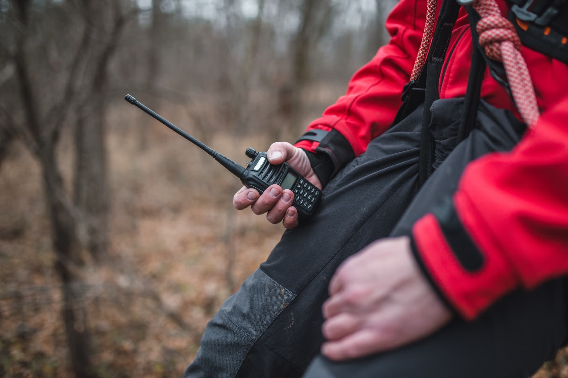 Search and rescue responder holding a handheld radio in the field
